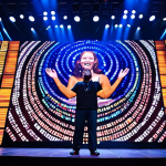 Technology Integration**

"A grand stage bathed in vibrant LED light, displaying dynamic visuals and song lyrics, captivating a large audience, fully clothed, appropriate attire, safe for work, professional concert photography, perfect anatomy, natural proportions, family-friendly."

**